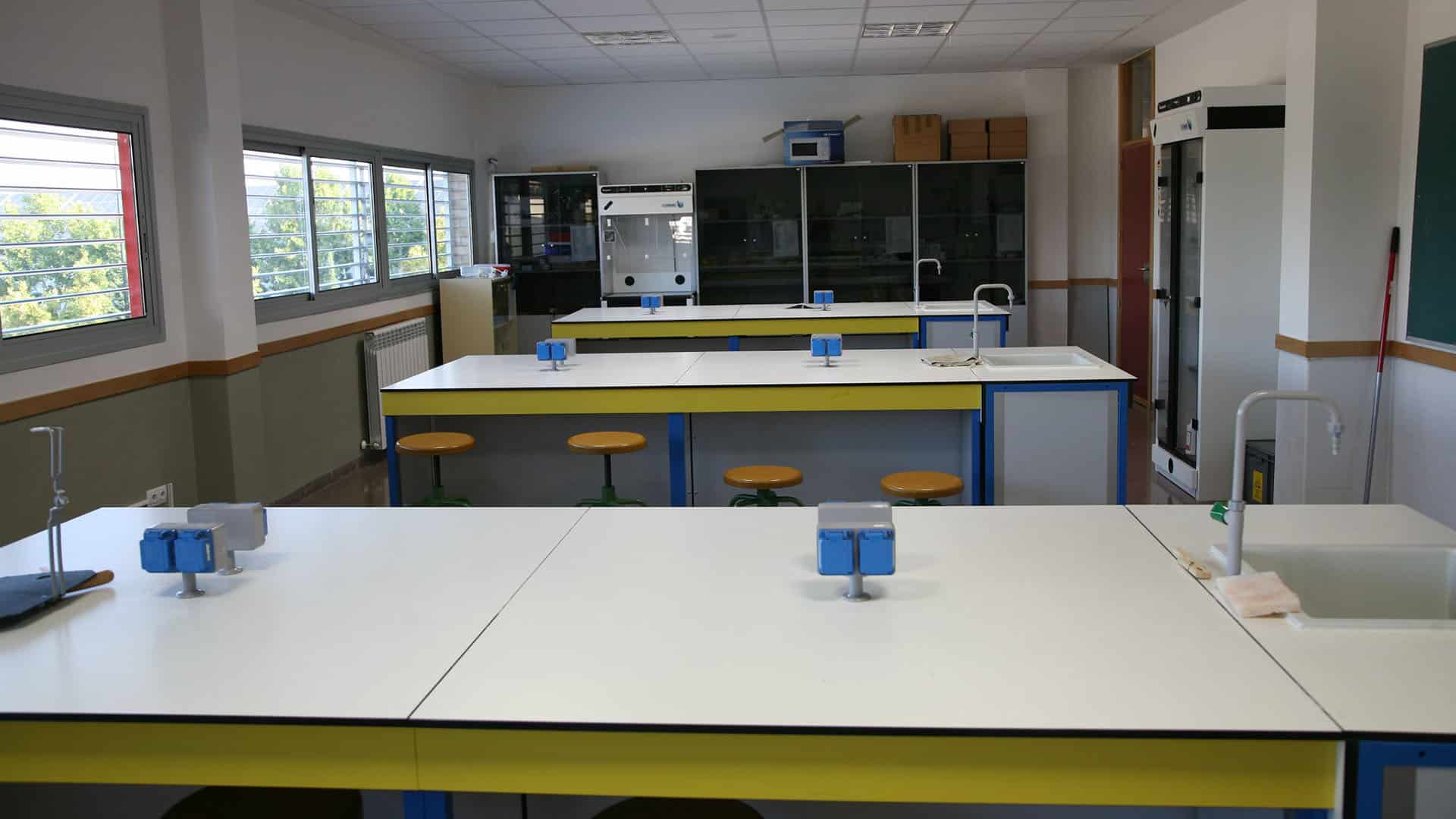 Laboratorio de química de un instituto de secundaria en Zaragoza con mesas de trabajo, fregaderos, taburetes y armarios.