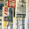 Primer plano de portadas de diferentes periódicos europeos colocados en los soportes de metal.