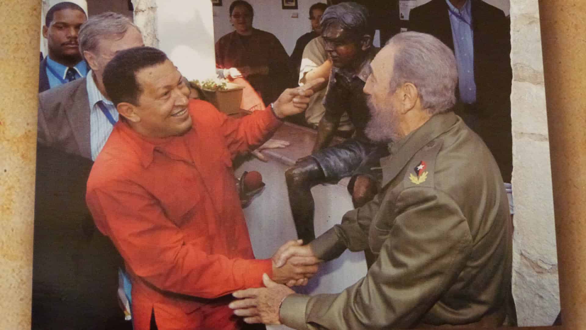 Hugo Chávez y Fidel Castro se estrechan la mano en la Casa Museo de Ernesto Che Guevara rodeados de asistentes.