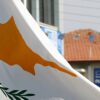 The flag of Cyprus flying in the foreground during an outdoor event.