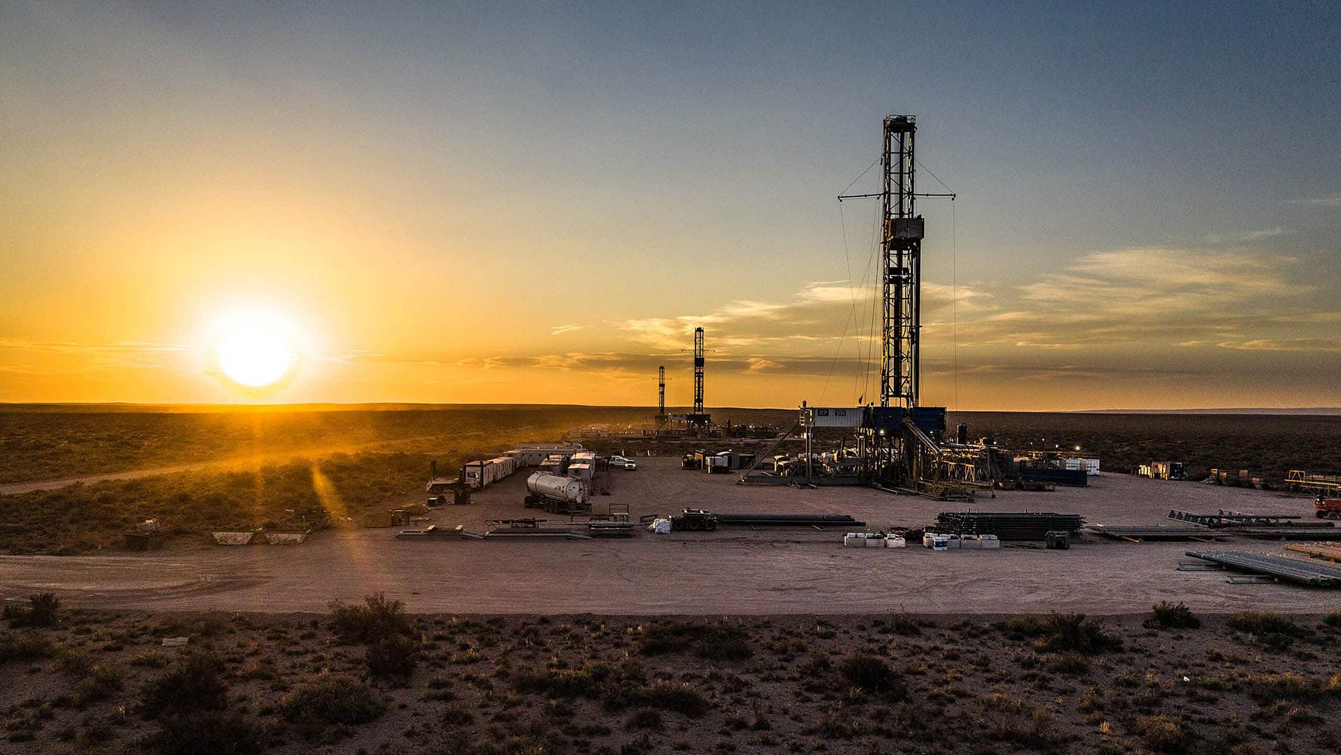 Panorámica de una planta de procesamiento de gas en Vaca Muerta (Argentina), una zona árida con vegetación baja al atardecer.