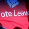 A close-up of a person wearing a red T-shirt with a purple cardigan left open. The T-shirt has the phrase ‘Vote Leave’ printed in white letters –a pro-Brexit slogan used during the 2016 referendum on the UK’s membership of the EU.