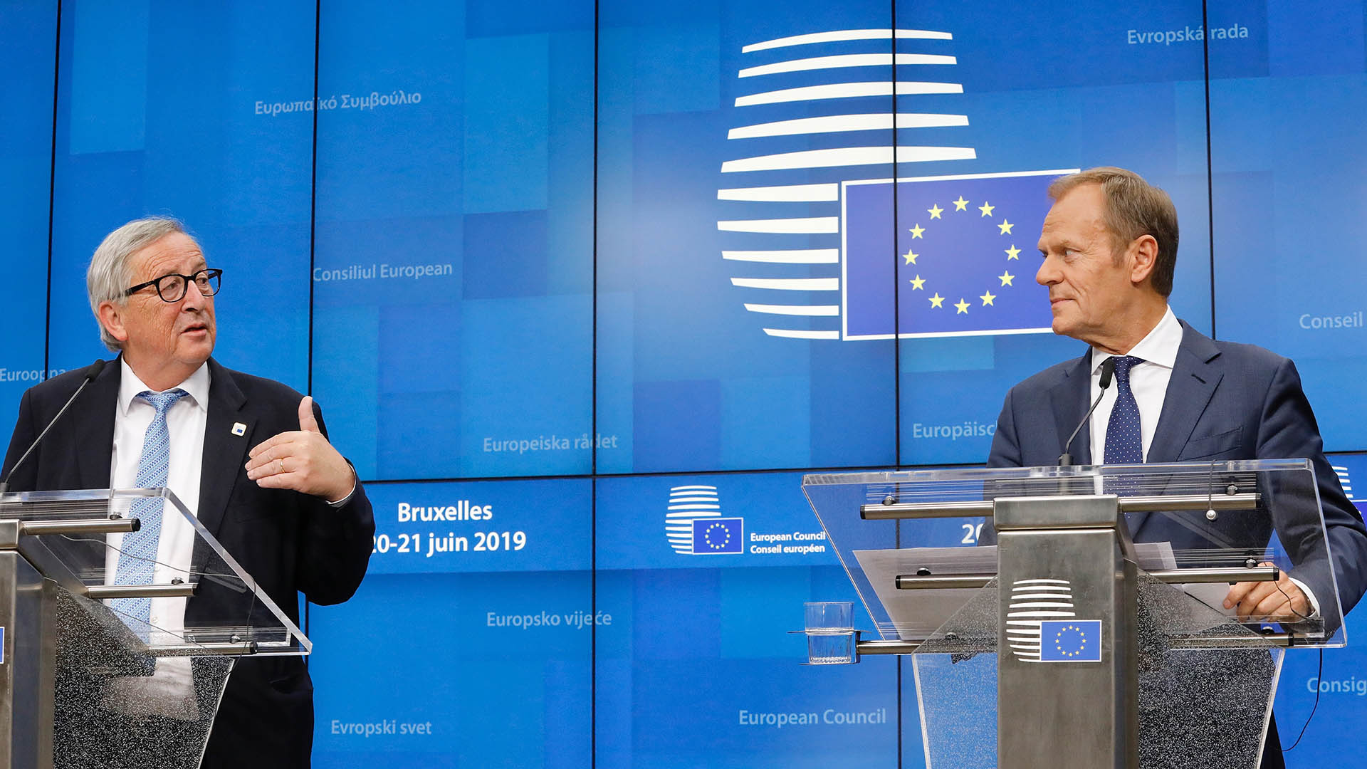Jean-Claude Junker (a la izquierda) y Donald Tusk (a la derecha), de pie tras atriles con micrófonos y delante de un panel azul con logos del Consejo Europeo, durante la rueda de prensa tras el Consejo Europeo (20/06/2019) en Bruselas, Bélgica.