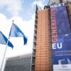 Pancarta del “Plan de Recuperación para Europa” o Next Generation EU en la fachada del edificio Berlaymont, sede de la Comisión Europea en Bruselas, Bélgica. Al lado izquierdo, tres banderas de la UE ondean en sus respectivos mástiles.