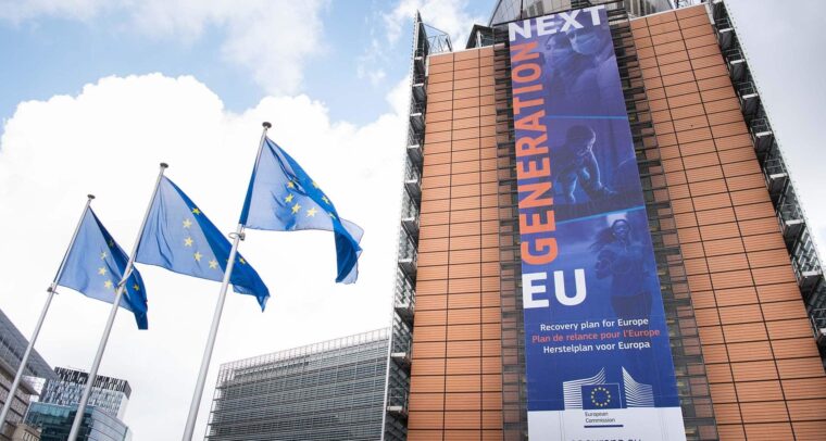 Pancarta del “Plan de Recuperación para Europa” o Next Generation EU en la fachada del edificio Berlaymont, sede de la Comisión Europea en Bruselas, Bélgica. Al lado izquierdo, tres banderas de la UE ondean en sus respectivos mástiles.
