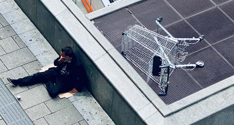 La lucha contra la desigualdad . Mujer con chaqueta y pantalones negros tumbada en unas escaleras de hormigón gris en Viena (Austria). Foto: Arno Senoner (@arnosenoner). Blog Elcano