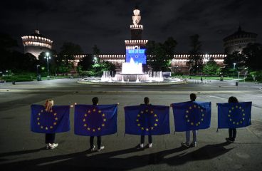 Personas portando la bandera europea frente al Castello Sforzesco (Milán, Italia) iluminado con motivo del Día de Europa 2021. Foto: Piero Cruciatti/©European Union, 2021. EC-Audiovisual Service. Blog Elcano