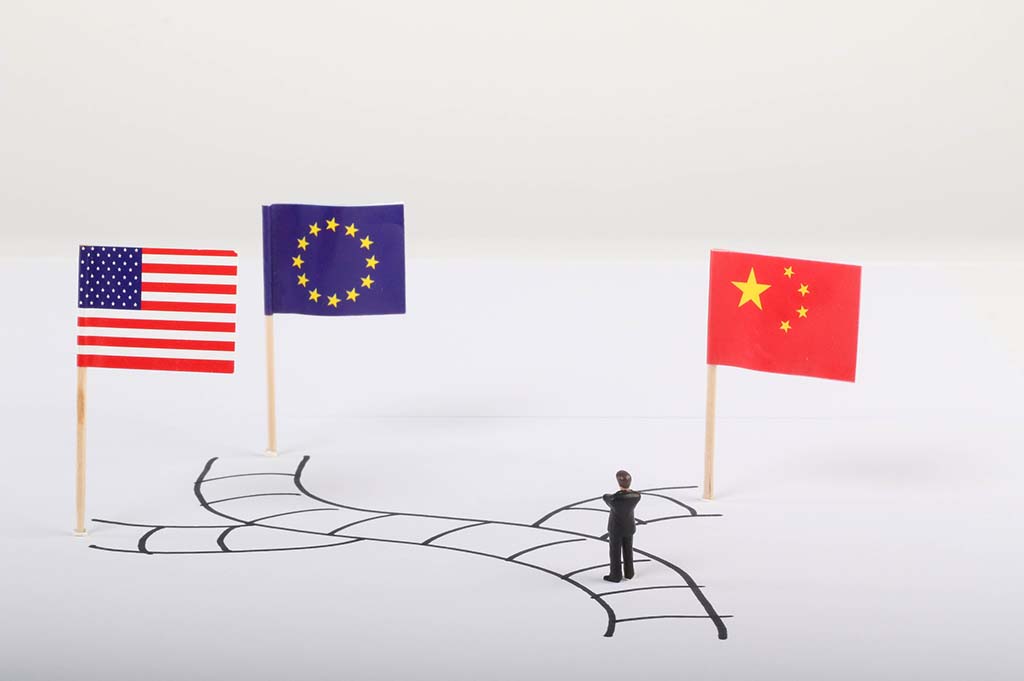 Hombre de pie en el camino con banderas de EE.UU., la Unión Europea y China. Hombre de pie en el camino con banderas de EE.UU., la Unión Europea y China. Blog Elcano