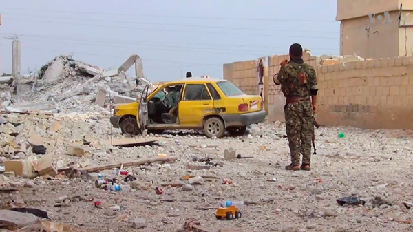 Un miliciano de las Fuerzas Democráticas Sirias ante un área destruida de la ciudad de Tabqa el pasado mayo. Foto: Voice of America (dominio público)