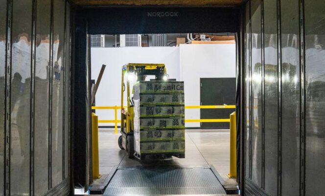 Problemas en las cadenas de suministro. Un operario conduce una carretilla elevadora amarilla y negra en un almacén