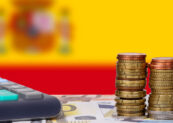 Ups and downs of the Spanish economy. Calculator with money and coins in front of flag of Spain