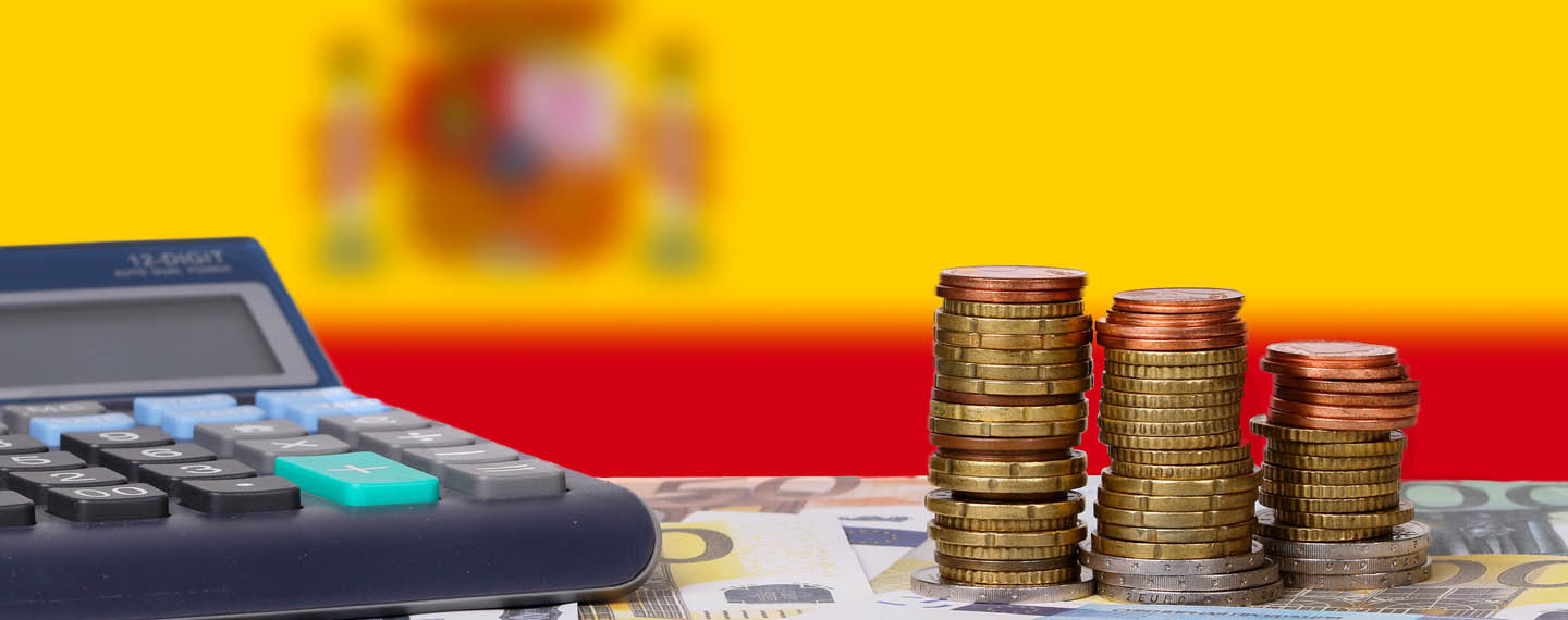 Ups and downs of the Spanish economy. Calculator with money and coins in front of flag of Spain