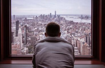 La intimidad de la mente. Hombre con camisa gris mirando los edificios de una ciudad durante el día
