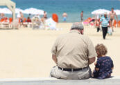 Children. An old man sitting besides a girl on a bench in a beach