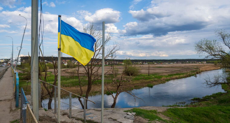 Una bandera de Ucrania ondea junto a un puente sobre el río Irpin, al lado de Hostomel, en las afueras de la ciudad de Kyiv