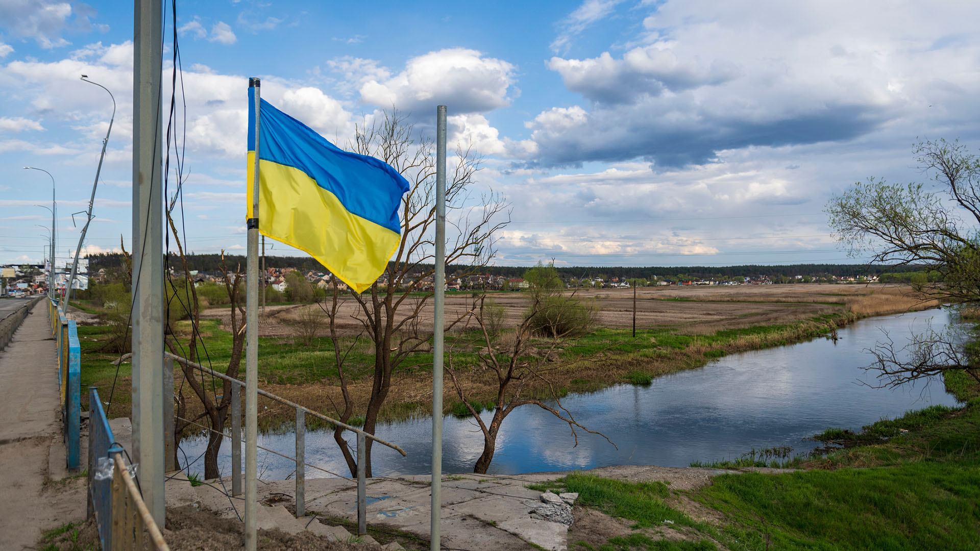 Una bandera de Ucrania ondea junto a un puente sobre el río Irpin, al lado de Hostomel, en las afueras de la ciudad de Kyiv