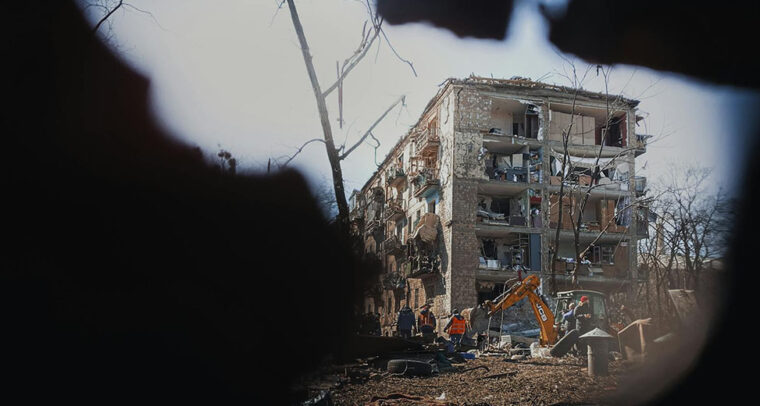Obreros y una máquina excavadora trabajan en los alrededores de un edificio destruido por los bombardeos en Kyiv en marzo de 2022. Guerra en Ucrania