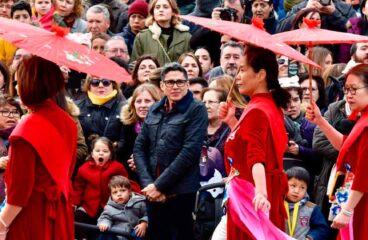 Crowds of people at the Chinese New Year parade in the streets of the Usera neighbourhood, Madrid (Spain). At the front, women dressed in traditional red costumes and umbrellas to welcome the year of the pig