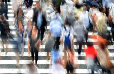 Barómetro del Real Instituto Elcano. Imagen desenfocada de una multitud de personas cruzando por un paso de zebra en una calle
