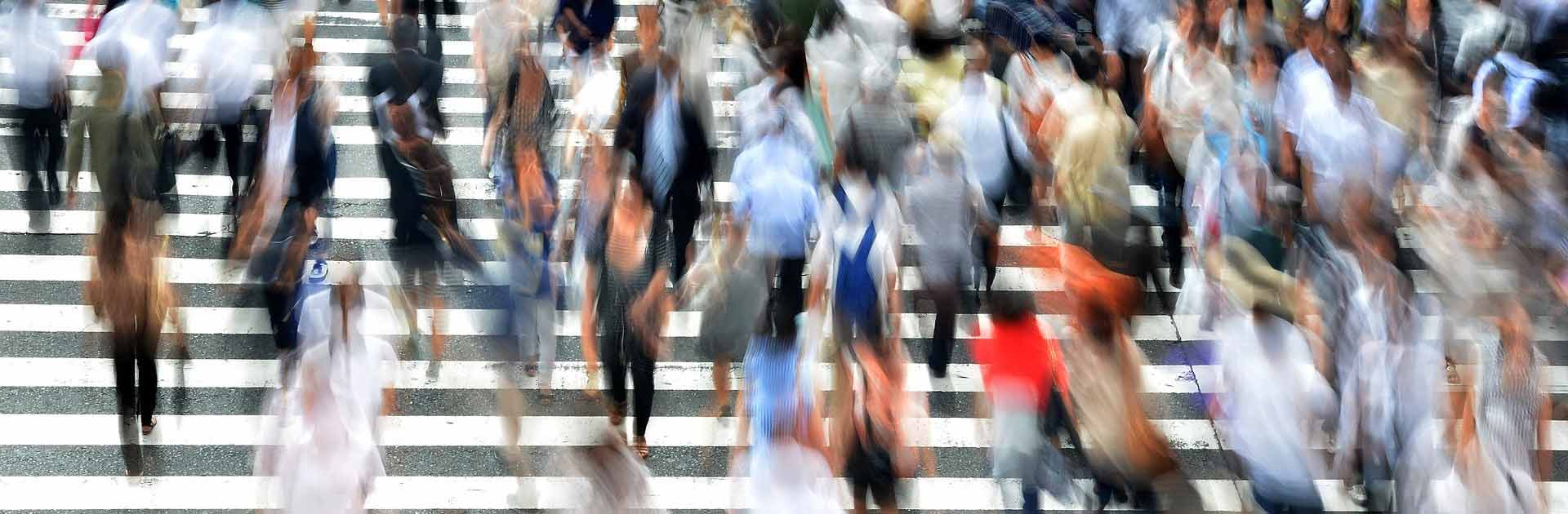 Barómetro del Real Instituto Elcano. Imagen desenfocada de una multitud de personas cruzando por un paso de zebra en una calle