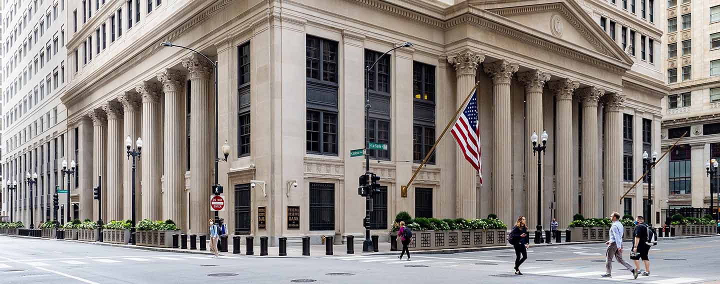 Inflation-financial stability trade-off. People crossing the street at a traffic light in front of the Federal Reserve Bank headquarters building in Chicago, Illinois (US)