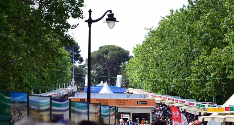 Image of the 2013 Madrid Book Fair in the Retiro Park with a crowd of people, the stands and the central pavilions
