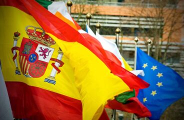 Consejo de la UE. Bandera de España en primer plano con la bandera de la UE al fondo en la sede del Parlamento Europeo en Bruselas