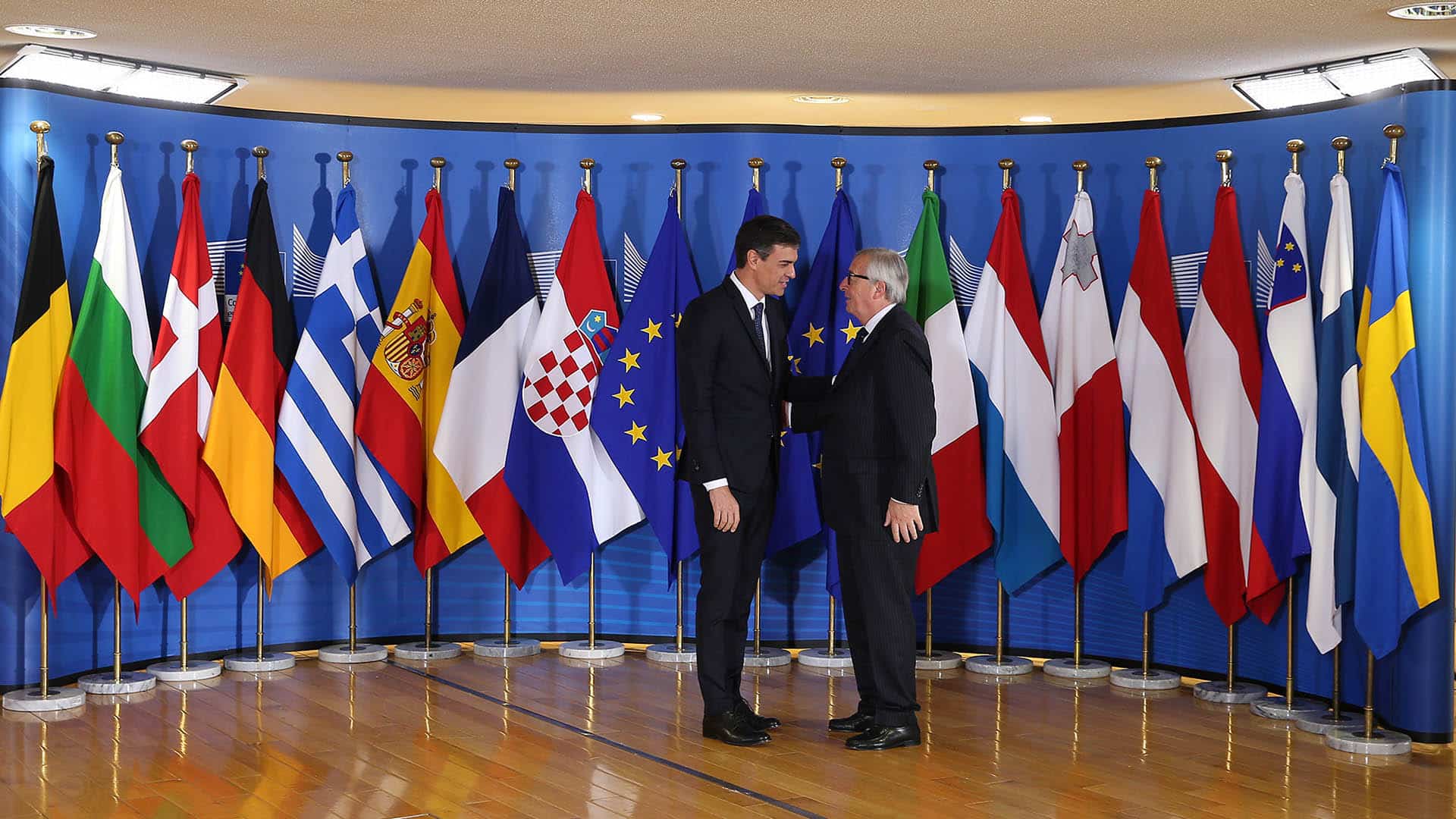 Pedro Sánchez (presidente del Gobierno de España) y Jean-Claude Juncker (presidente de la Comisión Europea) en la recepción de una reunión informal sobre asuntos de migración y asilo en Bruselas, Bélgica. Al fondo las banderas de los Estados miembros de la UE (24/06/2018).