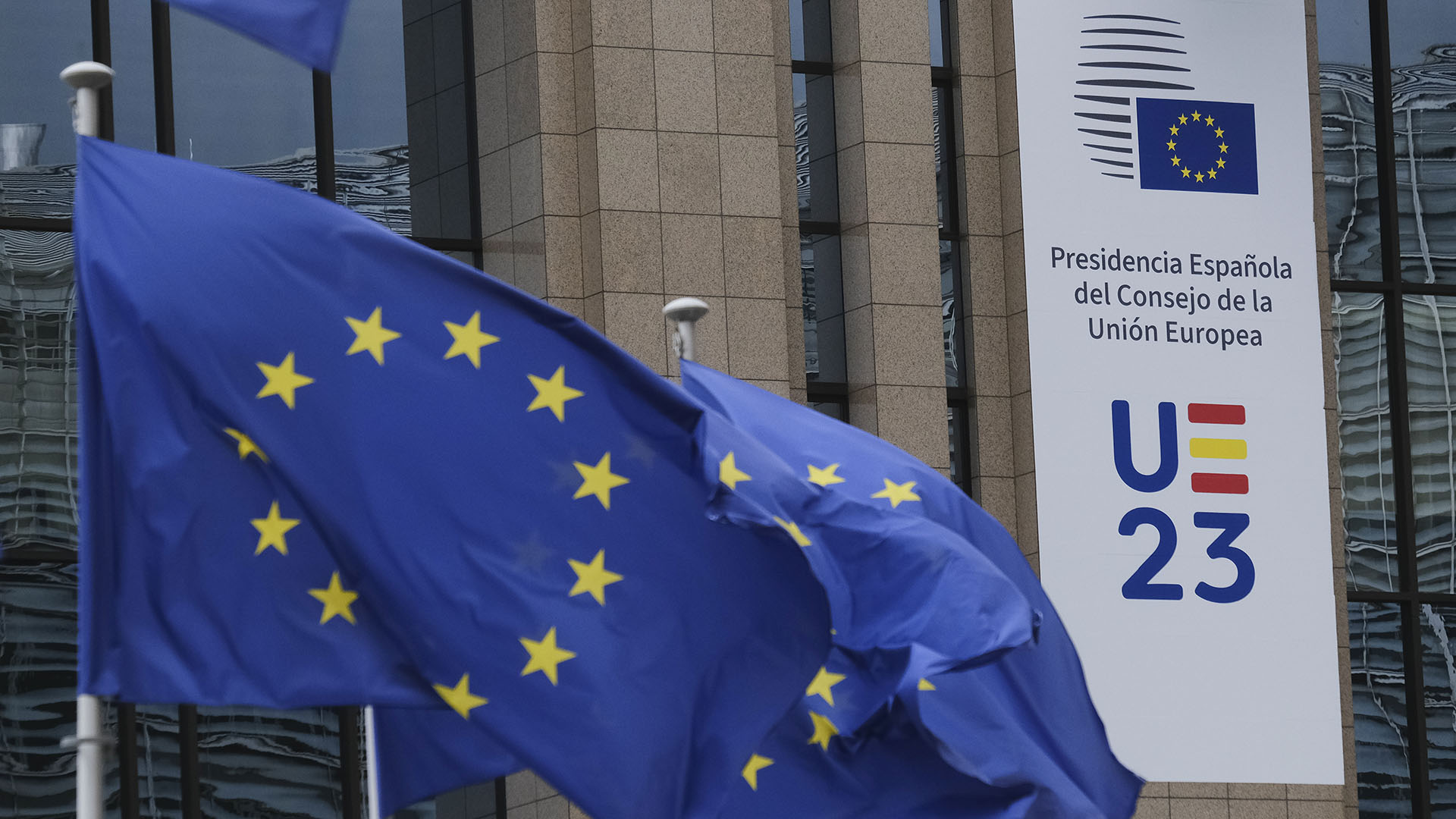 Banderas de la UE y banner con el logo de la Presidencia Española del Consejo de la UE como decoración en el edificio Europa en Bruselas, Bélgica.
