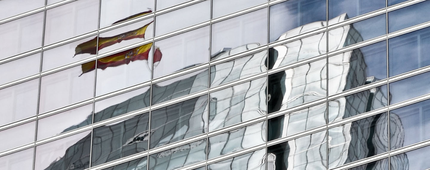 Spanish flag reflected in the windows of a building in the Cuatro Torres Business Area in Madrid (Spain)