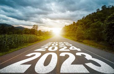 Texto año 2023, 2024, 2025 escrito en medio de una carretera de asfalto con el atardecer al fondo, en un paisaje rural y boscoso. Concepto de planificación, meta, desafío, resolución de año nuevo