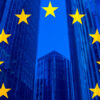Concepto de política, negocios, finanzas y ampliación de la Unión Europea con la bandera de la UE sobre rascacielos y edificios corporativos de fondo