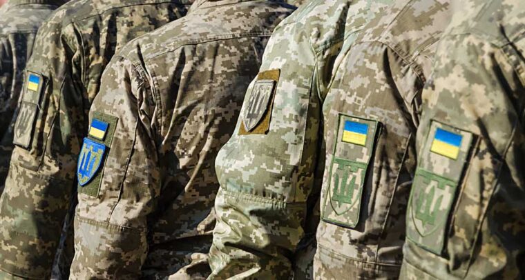 Brazos de soldados de las Fuerzas Armadas ucranianas, con las banderas y escudos de Ucrania en sus insignias, en un desfile militar