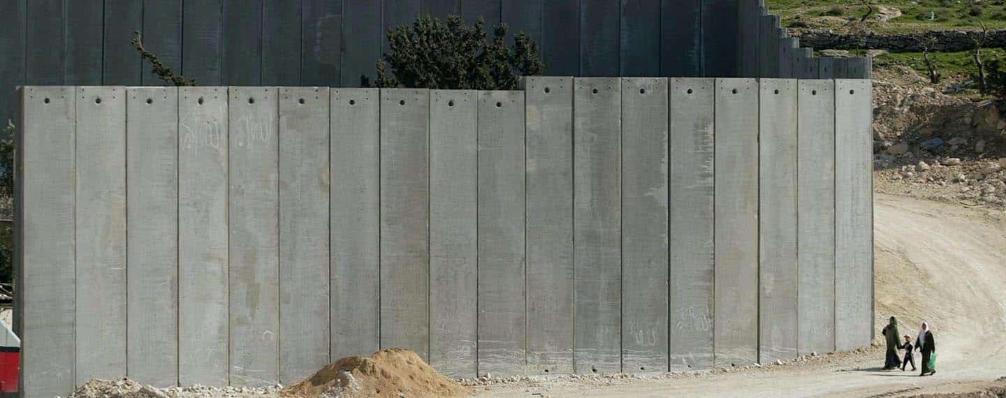 Una familia palestina pasa junto a una sección de la controvertida “barrera de seguridad” de Israel en la ciudad cisjordana de Abu Dis, en las afueras de Jerusalén. Imagen de 2004