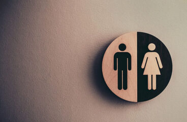 Foto de la señalización de una sala de descanso la representación binaria de géneros. A la izquierda, el símbolo de un hombre en negro sobre un fondo de madera, y ala derecha el símbolo de una mujer en madera sobre un fondo negro. Igualdad de Género