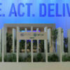 Detail of the COP28’s Trade House pavilion in Dubai, United Arab Emirates. Background: a soft blue curtain with the words “UNITE. ACT. DELIVER”. Foreground: a stage with plants and a big white poster with the printed logos of the UNFCC and the COP28 UAE