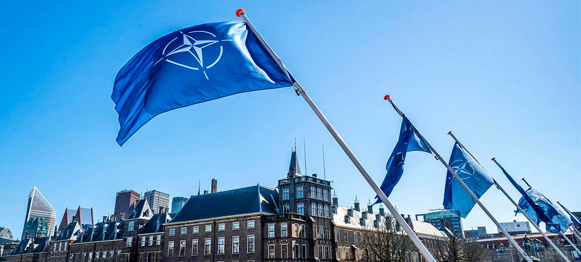NATO flags flying in The Hague, The Netherlands. Background: The Hague by day, with blue skies.