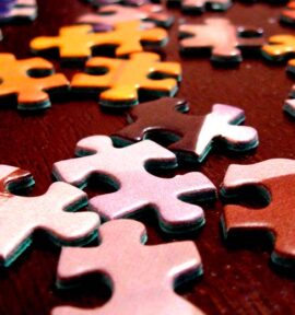 Piezas de puzle multicolor sobre una mesa marrón.