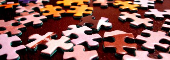 Piezas de puzle multicolor sobre una mesa marrón.