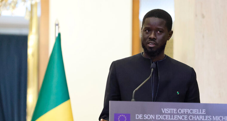 El nuevo presidente de Senegal, Bassirou Diomaye Faye, durante la rueda de prensa con motivo de la visita de Charles Michel, presidente del Consejo Europeo, en Dakar. Fondo: Banderas de Senegal y de la Unión Europea.