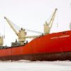 Red Russian icebreaker in the icy waters of the North Pole during the day.