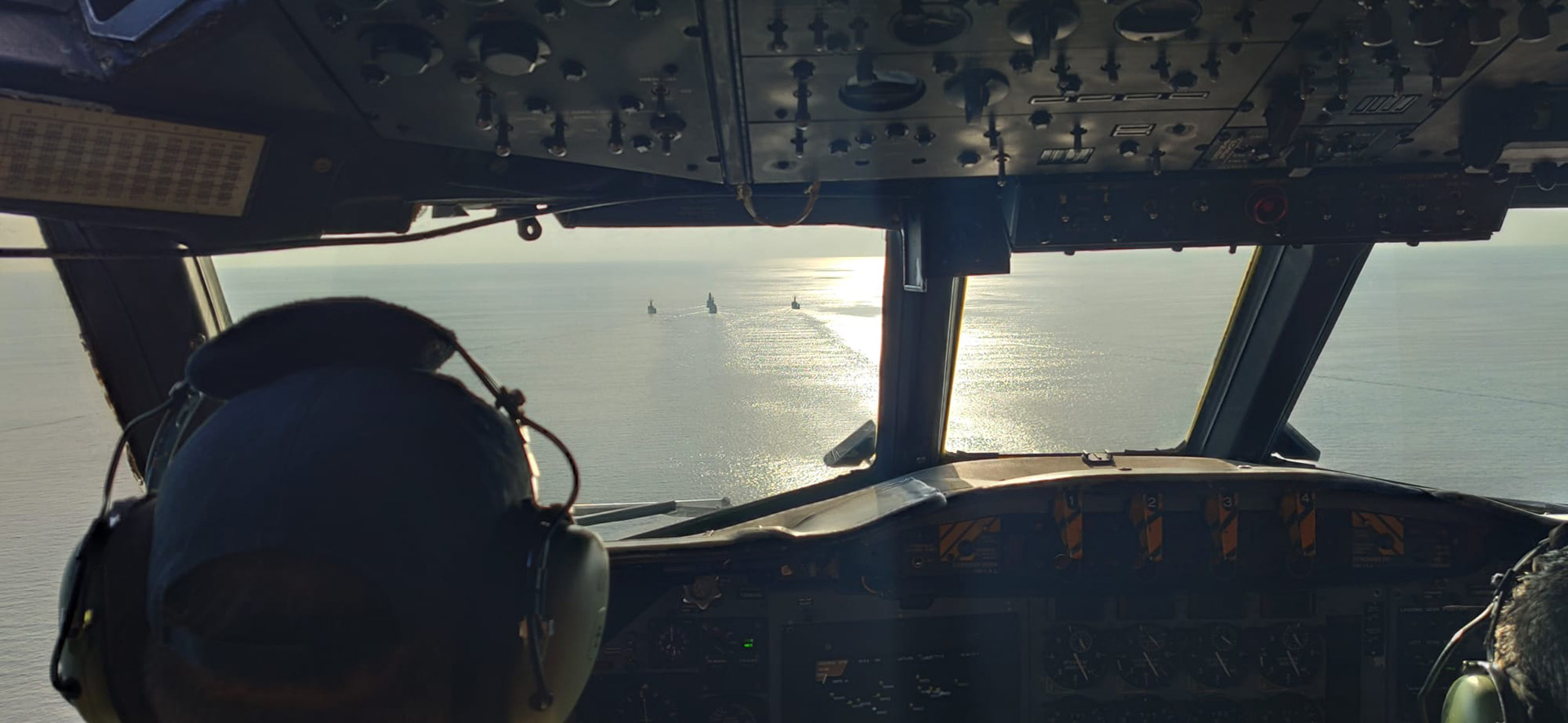 Daytime view from the cockpit of an aircraft of 4 Spanish Navy ships in a demonstration of the European Union naval force Operation Atalanta, with calm seas and partly cloudy skies