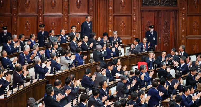 Shigeru Ishiba (de pie y al fondo) recibe los aplausos del resto de miembros (sentados) tras la votación en la Cámara de Representantes y la Cámara de Consejeros de su nominación como primer ministro de Japón.