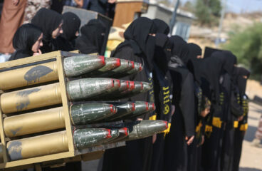 Grupo de mujeres vestidas de negro, con el rostro cubierto, asisten a un campamento militar de verano para jóvenes, organizado por las Brigadas Al-Quds, el ala militar del Movimiento de la Yihad Islámica, dentro de uno de sus emplazamientos militares en la ciudad de Khan Yunis. En primer plano, se aprecian unos proyectiles