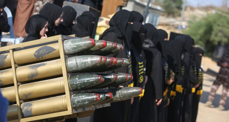 Grupo de mujeres vestidas de negro, con el rostro cubierto, asisten a un campamento militar de verano para jóvenes, organizado por las Brigadas Al-Quds, el ala militar del Movimiento de la Yihad Islámica, dentro de uno de sus emplazamientos militares en la ciudad de Khan Yunis. En primer plano, se aprecian unos proyectiles