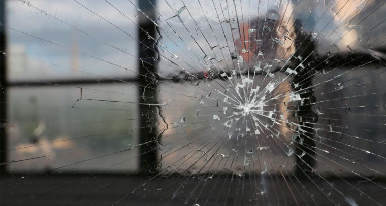 Image: A closeup shot of a cracked window during sunset with windows in the background. Elcano Forum on Global Terrorism