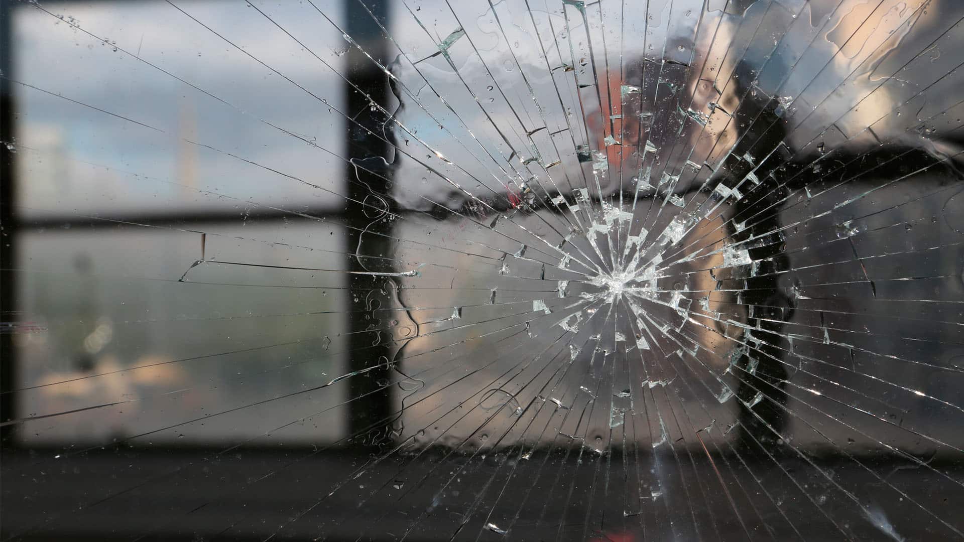 Image: A closeup shot of a cracked window during sunset with windows in the background. Elcano Forum on Global Terrorism