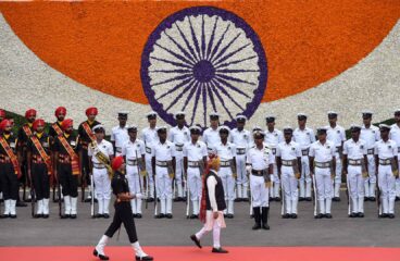 El primer ministro de la India, Narendra Modi, pasa revista a la Guardia de Honor durante el 77º acto del Día de la Independencia en el histórico Fuerte Rojo, el 15 de agosto de 2023 en Nueva Delhi. Modi es seguido por una guarda y al fondo un detalle de la bandera de India hecha con flores