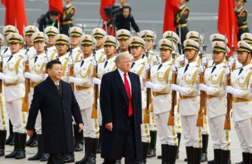 Primer plano de Donald Trump (a la derecha) camina junto a Xi Jinping (izquierda) sobre una alfombra roja en un evento en Pekín, China. En el fondo, una fila de guardias de honor chinos detrás de ellos, sosteniendo rifles. Victoria de trump