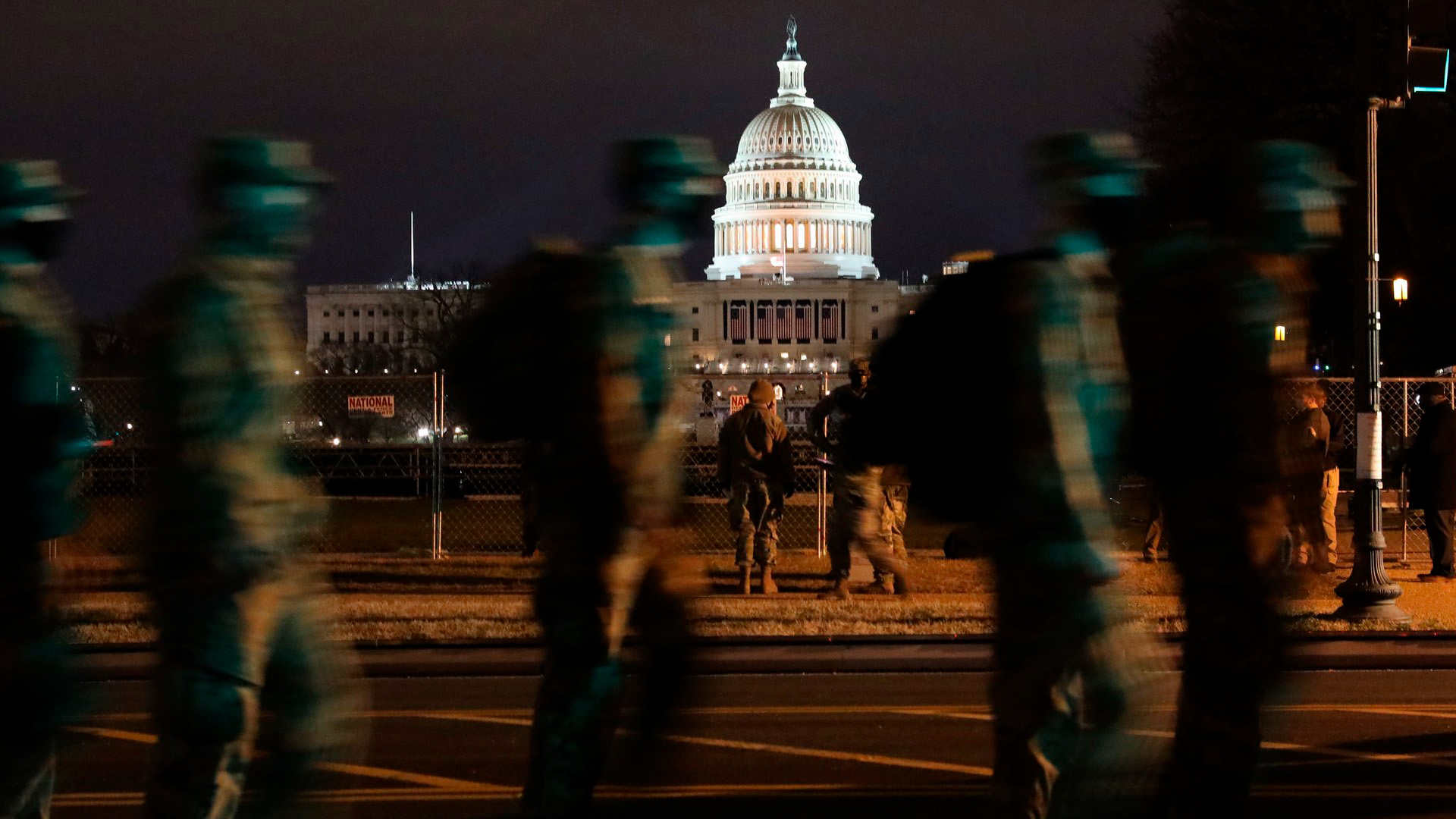 Imagen nocturna del Capitolio de Estados Unidos de noche. En primer plano, un grupo de soldados de la Guardia Nacional patrulla el perímetro. trump